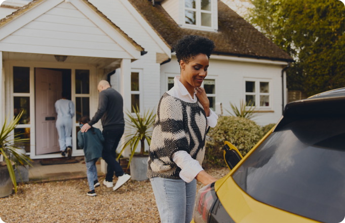 A credit union member standing beside a vehicle outside a home